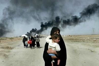 An Iraqi woman carries her young child as she flees with others from the southern Iraqi town of Basra in March 2003. This and accompanying photos are featured on the new MIT web site, Iraq: The Human Cost.