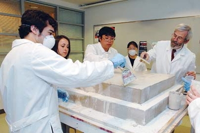 From left, MIT freshman Daniel Sauza, sophomore Stephanie Brown and seniors Ceryen Tan and Joyce Chen (in mask) work with materials science and nuclear engineering professor Linn Hobbs to cover limestone blocks with mortar as they build up their pyramid on the sixth floor of Building 16.