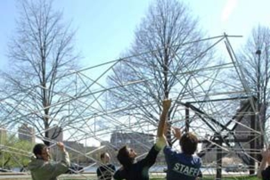 MIT students work on a new kind of solar generator that employs low-cost materials. Here they mount the frame of the concentrator (which will be mounted with mirrors) on the base near Tang Hall on Memorial Drive.