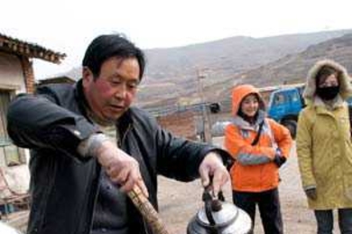 Tao Laoban works at cleaning one of the concrete solar cookers used in Tibet. A team of students, including some from MIT, has developed a more portable solar cooker.