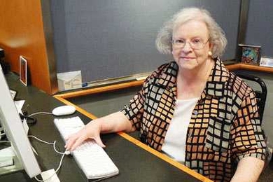 Kathy Barrett, a 45-year veteran of the Information Office at MIT, sits at the front desk to the office recently as her retirement date approaches.