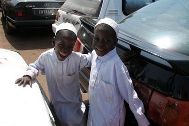 Two children in their best clothes climb between the cars in a gridlocked parking lot.  In the Bamako market cars are often parked three or four deep, and leaving means waiting for the owners of the cars in front of you to finish shopping. <a onclick="MM_openBrWindow('rotch-1-enlarged.html','','width=509, height=583')">
<span onmouseover="this.className='cursorChange';">
<strong>Open image gallery...