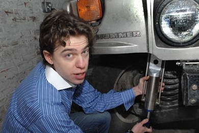 Zack Anderson, senior in elecrical engineering and computer sciences, holds a GenShock prototype up to a Humvee coil spring where it is installed.