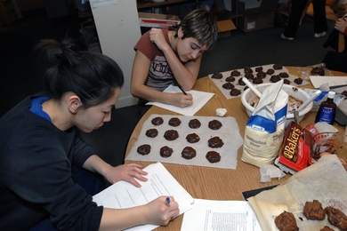 Senior Angie Chiang, foreground, and junior Taylor Williamson write notes on the chemistry they have learned by making "Death by Chocolate" cookies in Patti Christie's Kitchen Chemistry course, offered in the ESG kitchen.