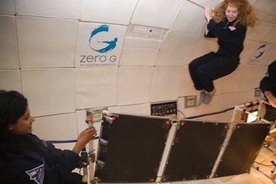 MIT student Tina Srivastava unfolds a solar panel during the micro-gravity flights, while senior Jillian James floats above.