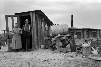 The Wardlaw couple at entrance of basement dugout home.