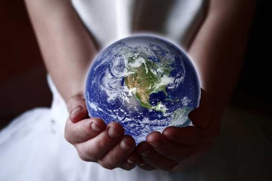 A person holds a glowing Earth in their hands. Their head and legs are not visible.