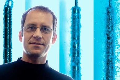 Professor Jacopo Buongiorno; background image shows a dispersion of nanoparticles in water that accelerates quenching of a hot rodlet (simulating a nuclear fuel rod), a feature that may be used to improve the thermal performance of nuclear reactors.