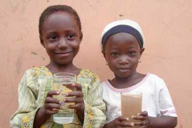 Two children in Ghana show the differences between water that has been cleaned with the Kosim filter, left, and water that has not.