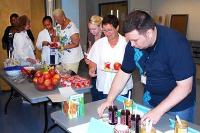 Greg Baker, a health educator in Community Wellness at MIT Medical (far right), sets out peanut butter and other healthy foods as MIT Medical employees line up to help themselves during the Breakfast Challenge.