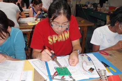 Students solder LEDs to a circuit board.