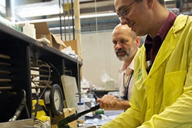 Gordon Kohse, left, and David Carpenter prepare an apparatus for burst testing of irradiated silicon carbide composite tubes in a radioactive materials laboratory at the Nuclear Reactor Laboratory.