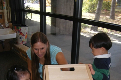 Karen Mikita, lead teacher at TCC Westgate, works with two preschool students engaged in dramatic play.