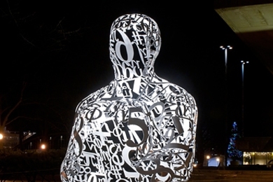 Alchemist, a sculpture by Jaume Plensa, is lit up at night.