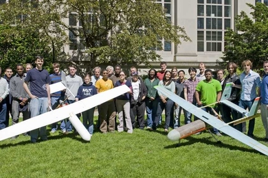 MIT students and faculty who worked on the unmanned aerial vehicle for Lincoln Laboratory are seen here with their first model on the left and the near-final product on the right.