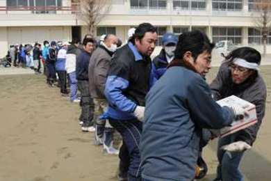 Japanese citizens receive food from a U.S. Navy helicopter as part of a disaster-relief and humanitarian-assistance operation.