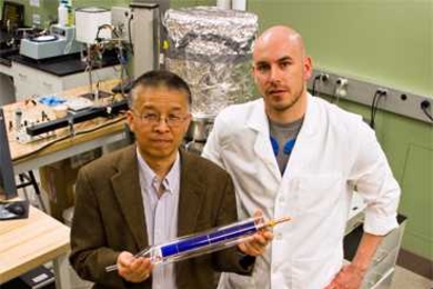 Doctoral student Daniel Kraemer, right, and Professor Gang Chen display a prototype of a flat-panel solar-thermoelectric generating device.