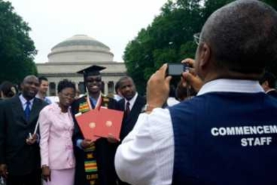 A Commencement volunteer takes a picture of a graduate and his family at the 2009 Commencement ceremonies.