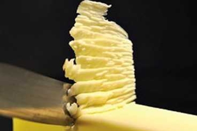 Sharp object skims off top of yellow block, forming a stack of soft residue.