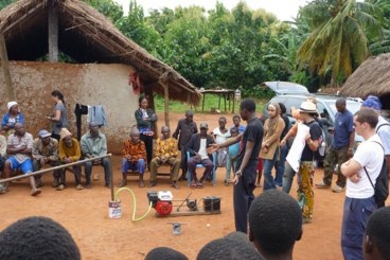 Members of a team that developed a system for generating gas from agricultural waste, which is attached to a small engine to generate power for charging cellphones, demonstrate their prototype at a village in Ghana.