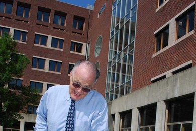 Dr. William Kettyle, medical director of MIT Medical, 'installs' one of the new signs that will be placed around Building E23, signifying the new tobacco-free zone within 25 feet of MIT Medical.