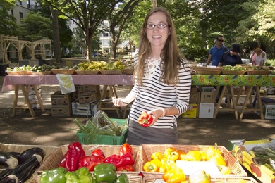 Graduate student Ann Bauer soaks up the sunshine and loads up her basket with fresh vegetables at the MIT Produce Market at East Campus.