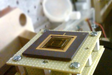 A new energy harvesting device converts low-frequency vibrations into electricity. The device, the size of a U.S. quarter, is shown mounted on a stand.