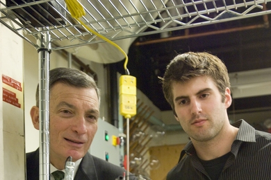 Professor Donald Sadoway and Materials Processing Center Research Affiliate David Bradwell observe one of their small test batteries in the lab. The battery itself is inside the heavily insulated metal cylinder at center, which heats it to 700 degrees Celsius.