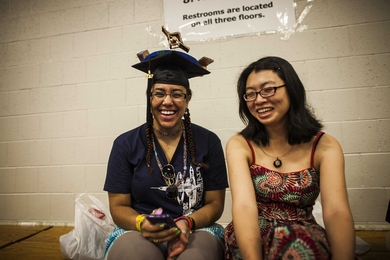 A student with a replica of Earth surrounded by satellites sits in Rockwell Cage awaiting the procession to Killian Court to begin.