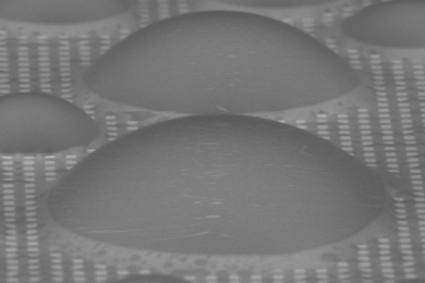 On a surface patterned with tiny pillars (white squares), and with a coating of a lubricant liquid that fills the spaces between the pillars, dome-shaped droplets of water condense but remain free to move quickly across the surface, unlike on conventional flat surfaces or ones with just the patterning, where they tend to stay stuck in place. The new surface treatment could provide a significant bo...