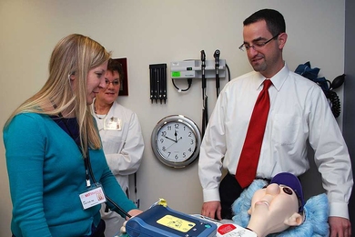 During an emergency drill at MIT Medical, Nurse Amy Chilton, left, and Internist Brian Ash attempt to “resuscitate” a life-size dummy that, in this mock scenario, has suffered cardiac arrest in Ash’s examination room. Triage Nurse Lynn Forgues, rear, acts as “recorder,” taking notes of times and activities, such as drugs administered and changes in heart rhythm.
