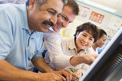 Four people near a computer monitor in classroom