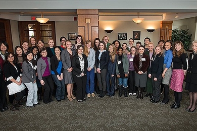 About 35 people pose together in an indoor lounge