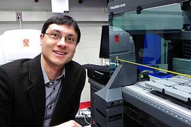 MIT Assistant Professor of Physics Jeff Gore in his lab with the Tecan Freedom Evo pipetting robot.