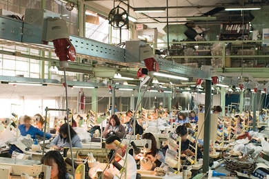Photo of a factory floor, with many dozens of workers seated at sewing machines
