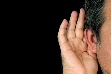 Human hand placed up against an ear
