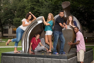 six students pose on large sculpture