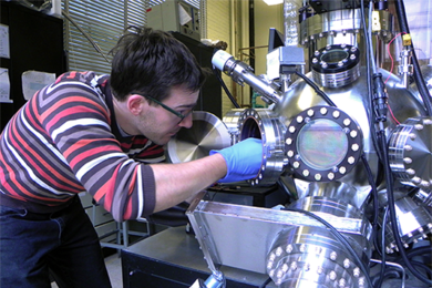 MIT Materials Science and Engineering graduate student Nicolas M. Aimon inserts a holder into a pulsed laser deposition chamber.