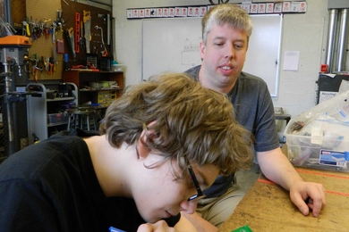 Daniel Sheen, a junior at the John D. O'Bryant School of Mathematics and Science, and frequent Saturday Thing participant, receives guidance from alumni volunteer Mike Allen while soldering a circuit board to be used for the musical laser harp.
