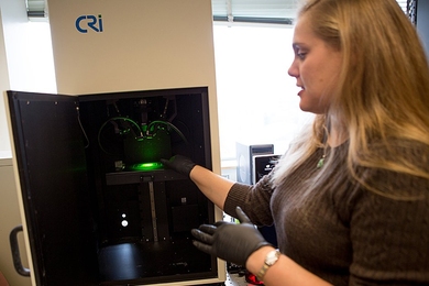 Postdoc Nicole Iverson demonstrates the instrument used to measure the fluorescent signal from nanotube sensors that detect nitric oxide.