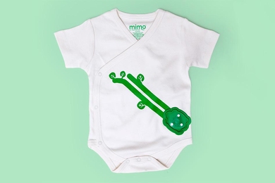 Rest Devices' Mimo kimono (shown here) has sensors embedded on the two green fabric stripes, resembling a vine with leaves, that track respiration. Attached at the end of the “vines” is a mount for a plastic module, resembling a turtle (not pictured), that captures the respiration data, as well as sleeping position, activity level, and body temperature. 