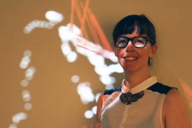 Architecture student Paloma Gonzalez Rojas standing in front of WalkAcross, her project that displays a real-time visualization of visitors' motion in the MIT Museum.
