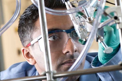 Man holding chemistry equipment up to look at it
