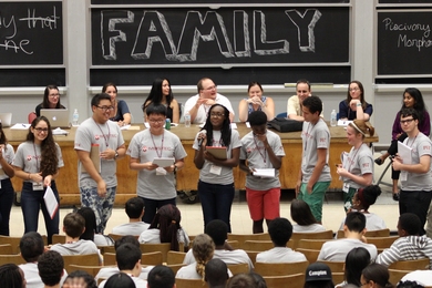 Group of students in front of chalkboard in lecture hall.