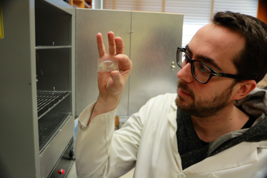 MIT postdoc Davide Ciceri holds a microfluidic device he designed to study leaching of potassium from the silicate mineral potassium feldspar. 
