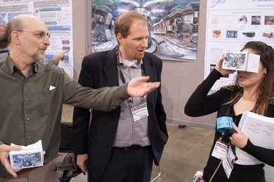 Josh Stillerman (left) and Bob Mumgaard help guide conference attendee Deedee Ortiz through virtual rooms of a 3-D tokamak fusion device.