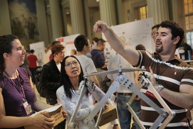 MIT MechE staff members Emilie Heilig (left) and Yvette Lai (center) listen to Daniel Gonzalez's presentation on his Triple Scissor Extender at the annual Mechanical Engineering Research Exhibition (MERE).