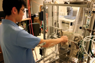 Kevin Kung, a Tata Fellow and PhD candidate in biological engineering, feeds rice husks into the torrefaction reactor in his lab at MIT. A thermochemical process will convert the biomass to a more energy-dense form, making it easier to transport and use as fuel.