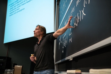 Tommi Jaakkola, a professor of electrical engineering and comptuer science at MIT, tosses chocolates to students during Introduction to Machine Learning, or 6.036.