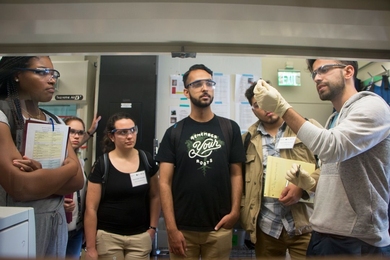 Chemical engineering postdoc Antoni Forner-Cuenca (far right) explains work in the Brushett Lab on advanced flow batteries for grid-level energy storage to 2017 MPC-CMSE Summer Scholars (l-r) Kaila Holloway, Gaetana Michelet, Alexandra Oliveira, Saleem Iqbal, and Alejandro Aponte-Lugo. Forner-Cuenca is holding carbon paper where battery reactions take place.  